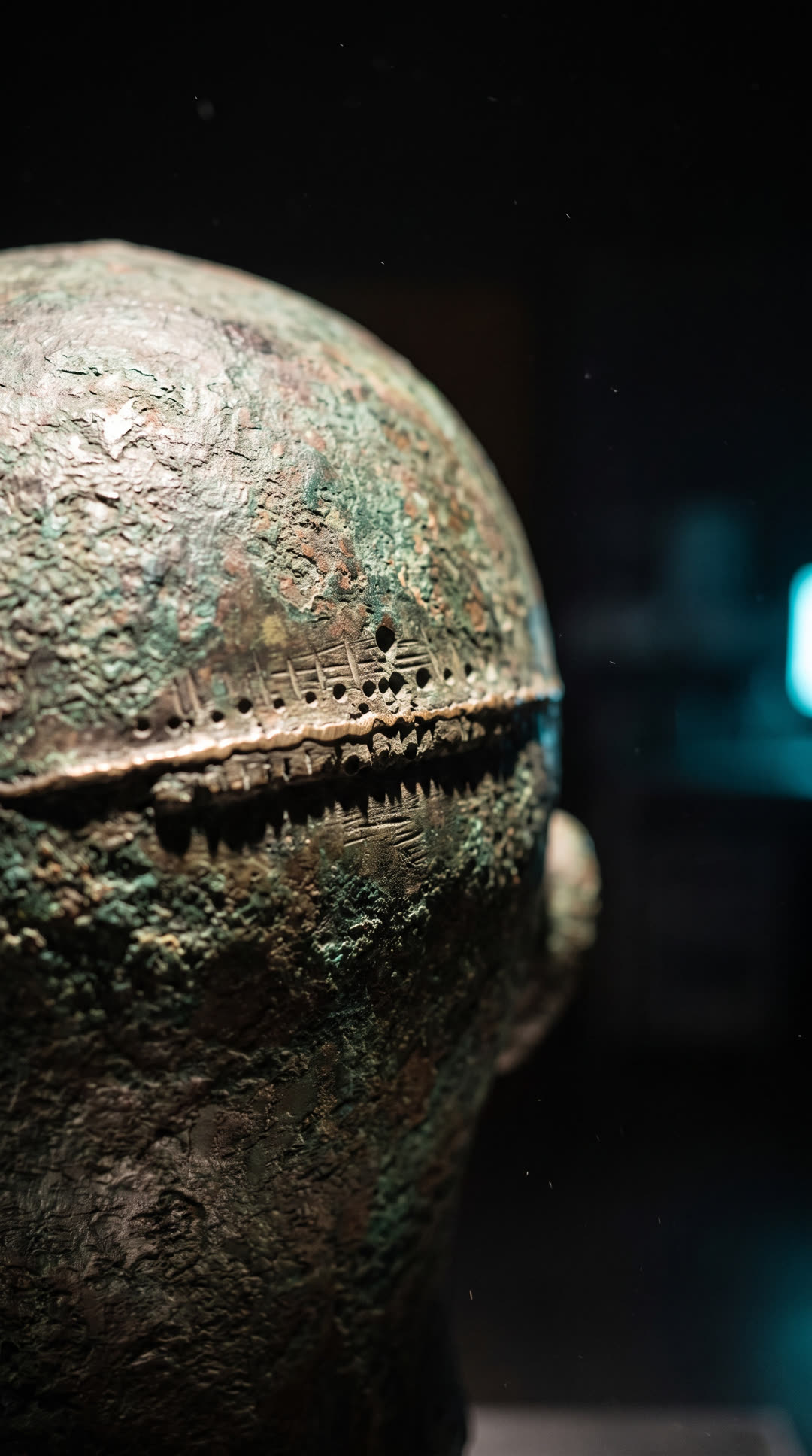 Macro di una vecchia saldatura di restauro che attraversa la nuca, una linea di lega più chiara sulla patina verde.